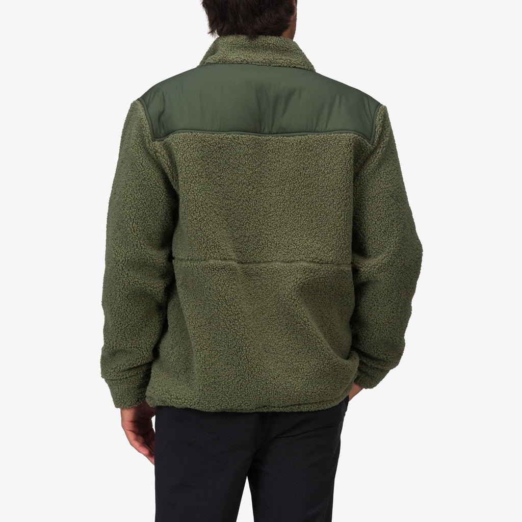 Back view of a man wearing an olive green Cooke Sherpa Jacket with a smooth shoulder panel, highlighting comfort and beach-inspired style.