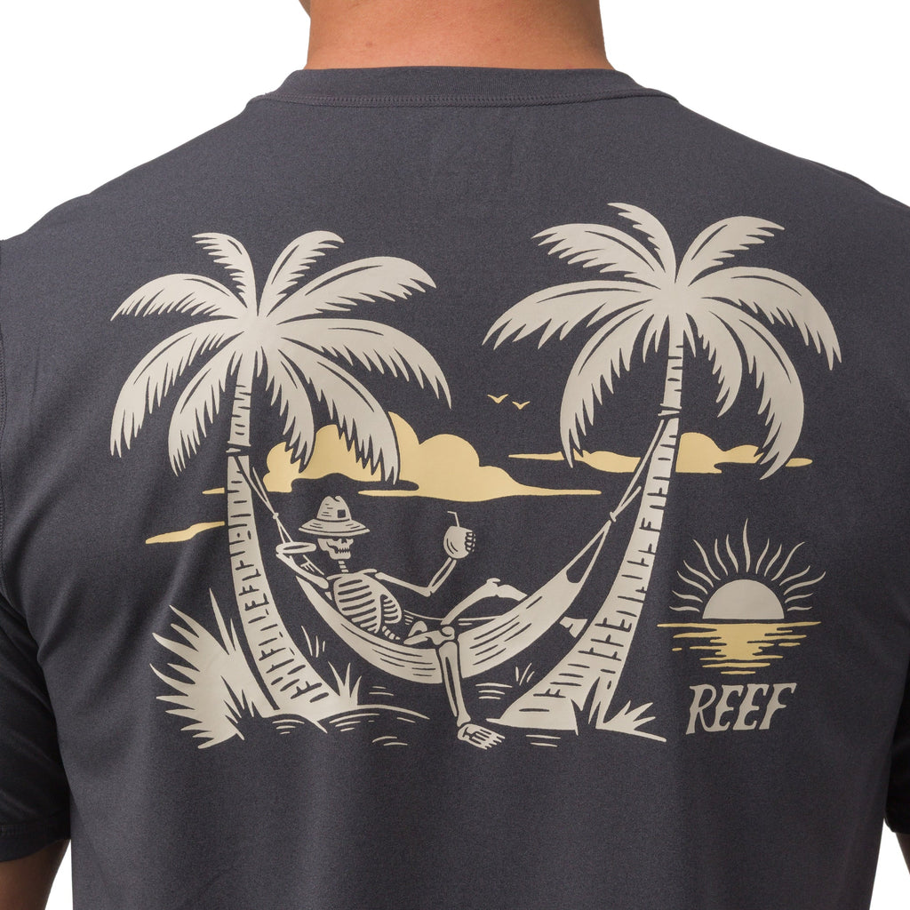 Back view close-up of Siesta Performance Shirt showing hammock skeleton graphic between palm trees on charcoal fabric.