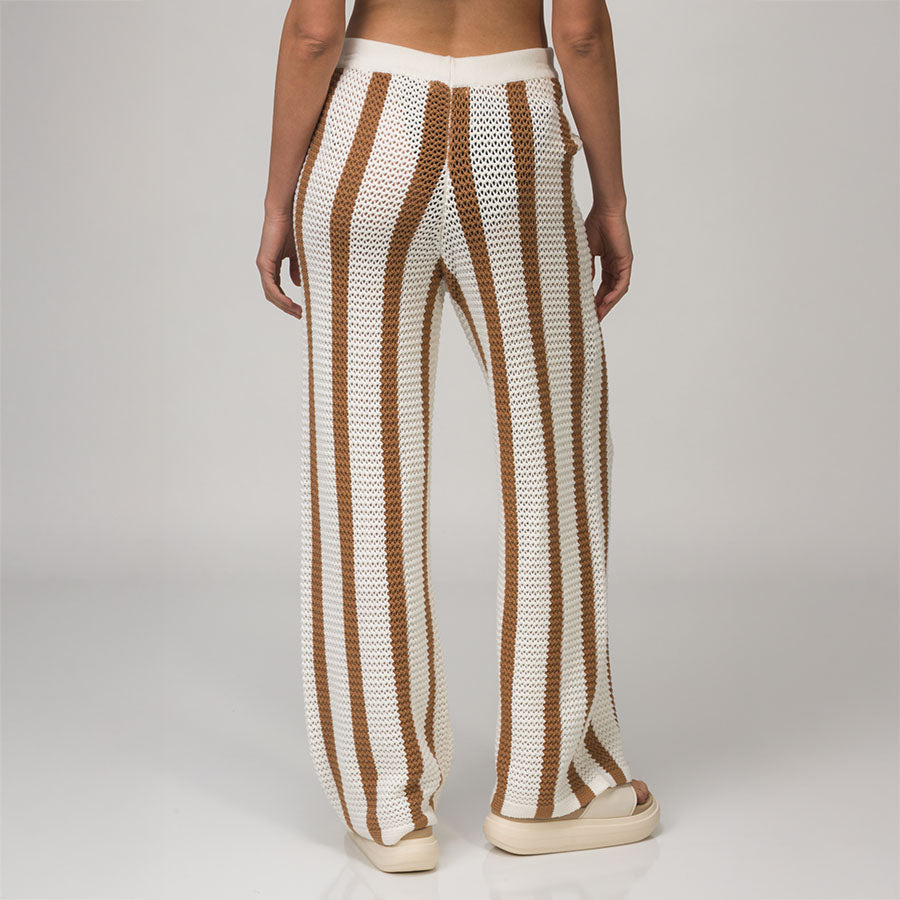 Back view of woman wearing Mika Sweater Pant with brown and white stripes, paired with beige sandals facing right.