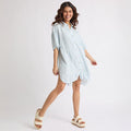 Woman wearing Ollie Striped Shirt Dress with light blue stripes, posing with left foot facing forward in white platform sandals