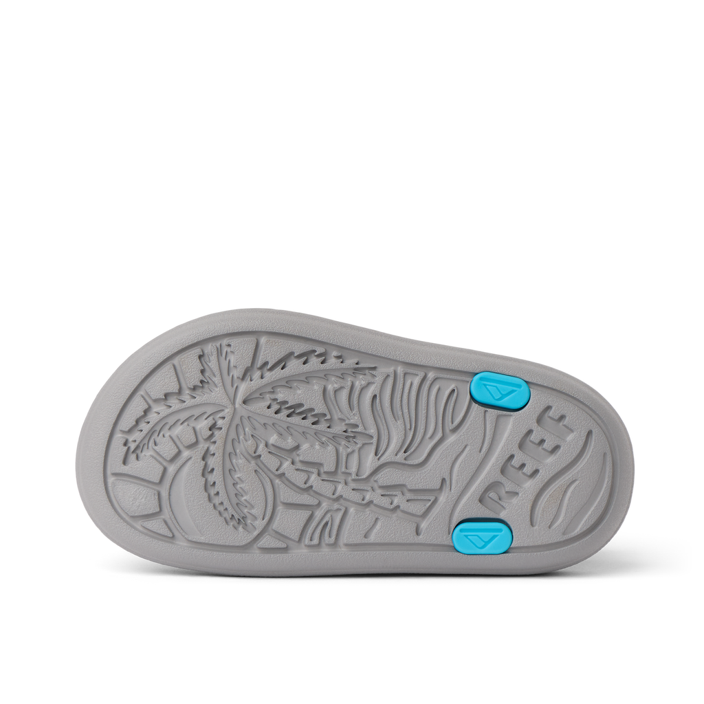 Little Totally Beachin boys sandal sole facing up, showing textured palm tree design and blue grip accents.