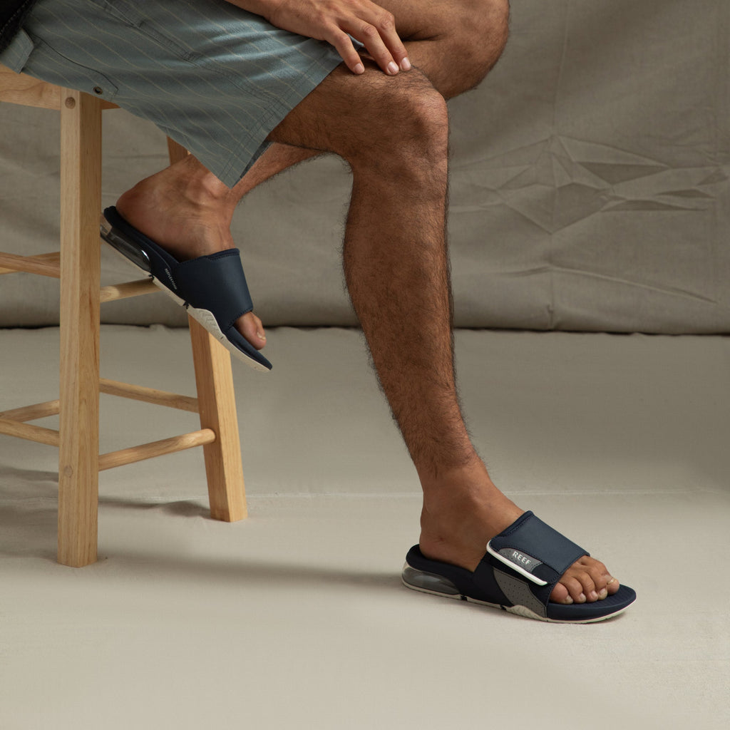 Fanning + Slide sandals on model facing right with navy blue and grey water-friendly straps, cushioned sole, and airbag heel comfort