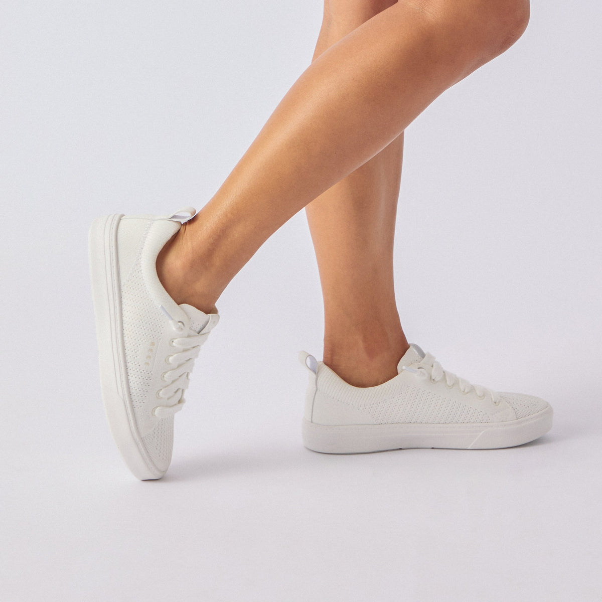 Side view of white Lay Day Lite sneaker on woman's feet, showcasing lightweight, breathable design and comfort features.