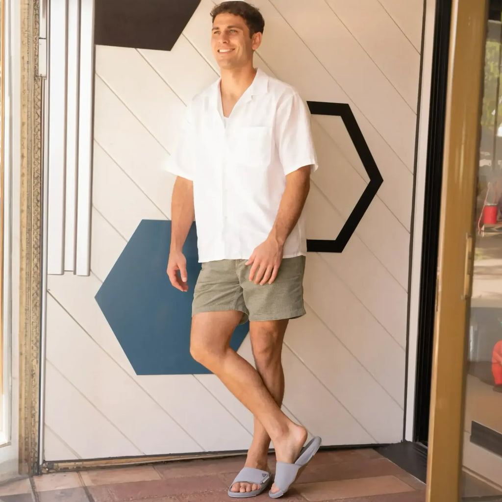 Man wearing Phantom Slab grey slides facing forward, showing comfortable, beach-inspired footwear with anatomical arch support.
