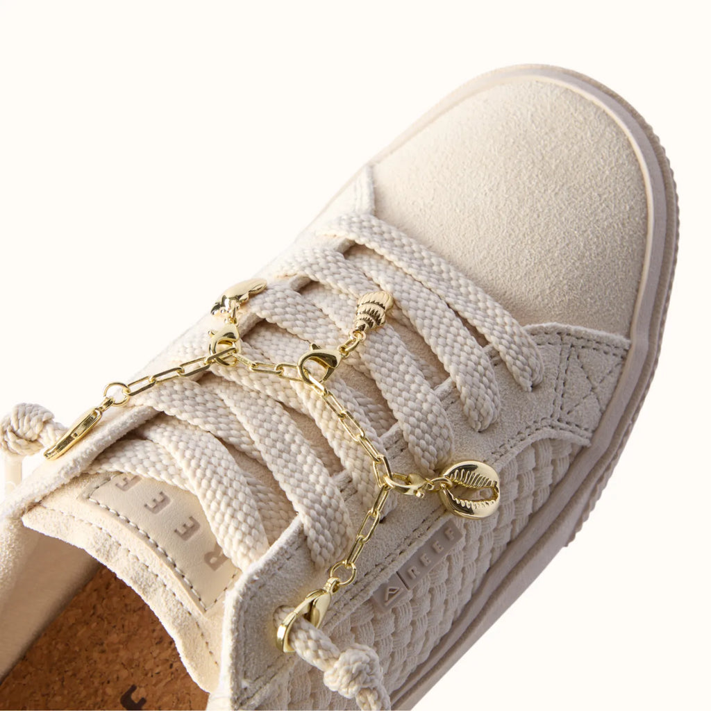 Lay Day Dawn x Jenny women's sneaker close-up on top showing soft neutral fabric, rope laces, and gold shell charm detail