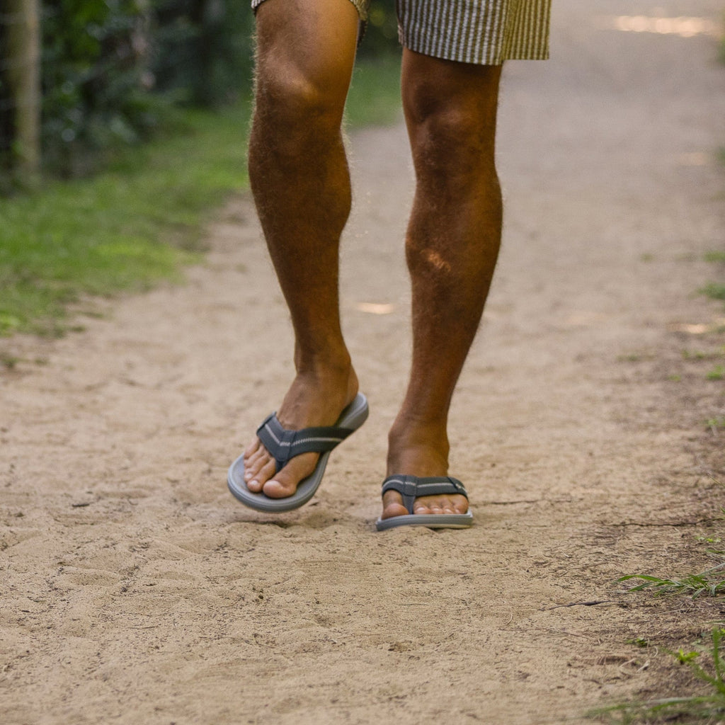 Men's feet wearing Cushion Phantom 2.0 flip flops walking on sandy path, right foot forward, showing top and side view.