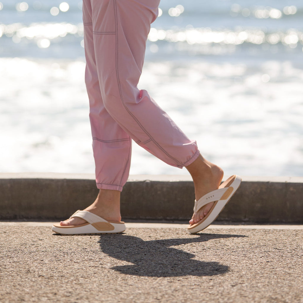 woman wearing Sydnee Swell Low Vintage with pink pants walking on the sidewalk by the ocean