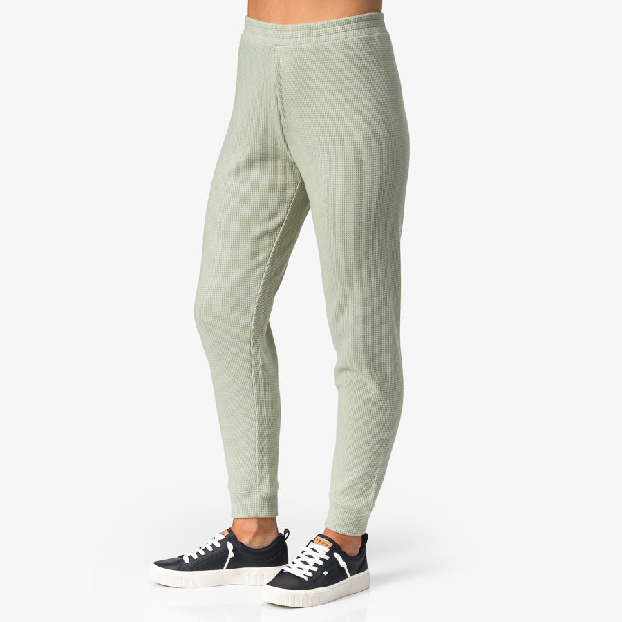 Tina Thermal Jogger in desert sage, side view showing lightweight, ribbed fabric and cuffed ankles, paired with navy sneakers.