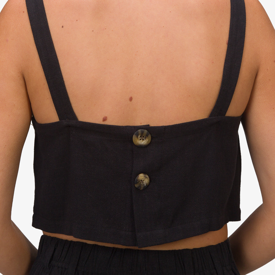 Back view of a woman wearing a black Tori Linen Tank with button details, showing the upper back and straps.