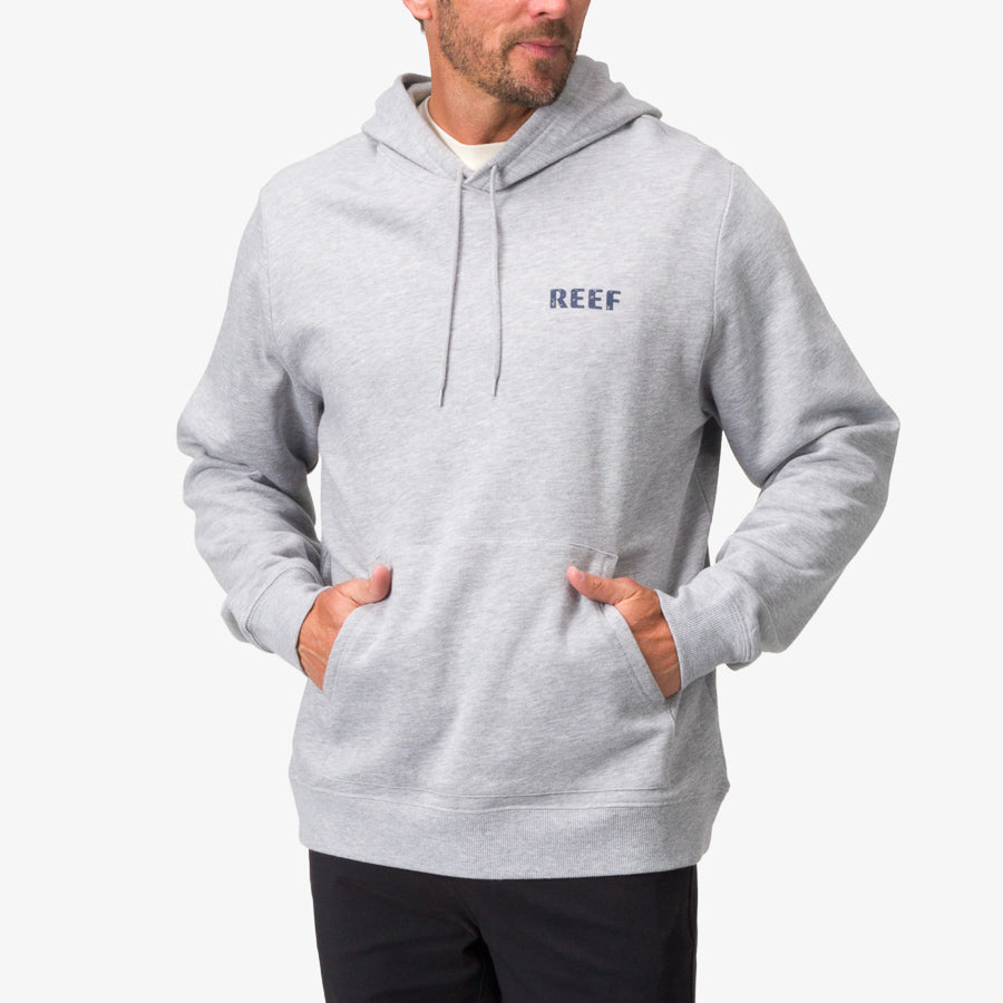 Man wearing a heather grey Wellie Too Hoodie with front pockets, surf-inspired comfort and REEF logo on chest.